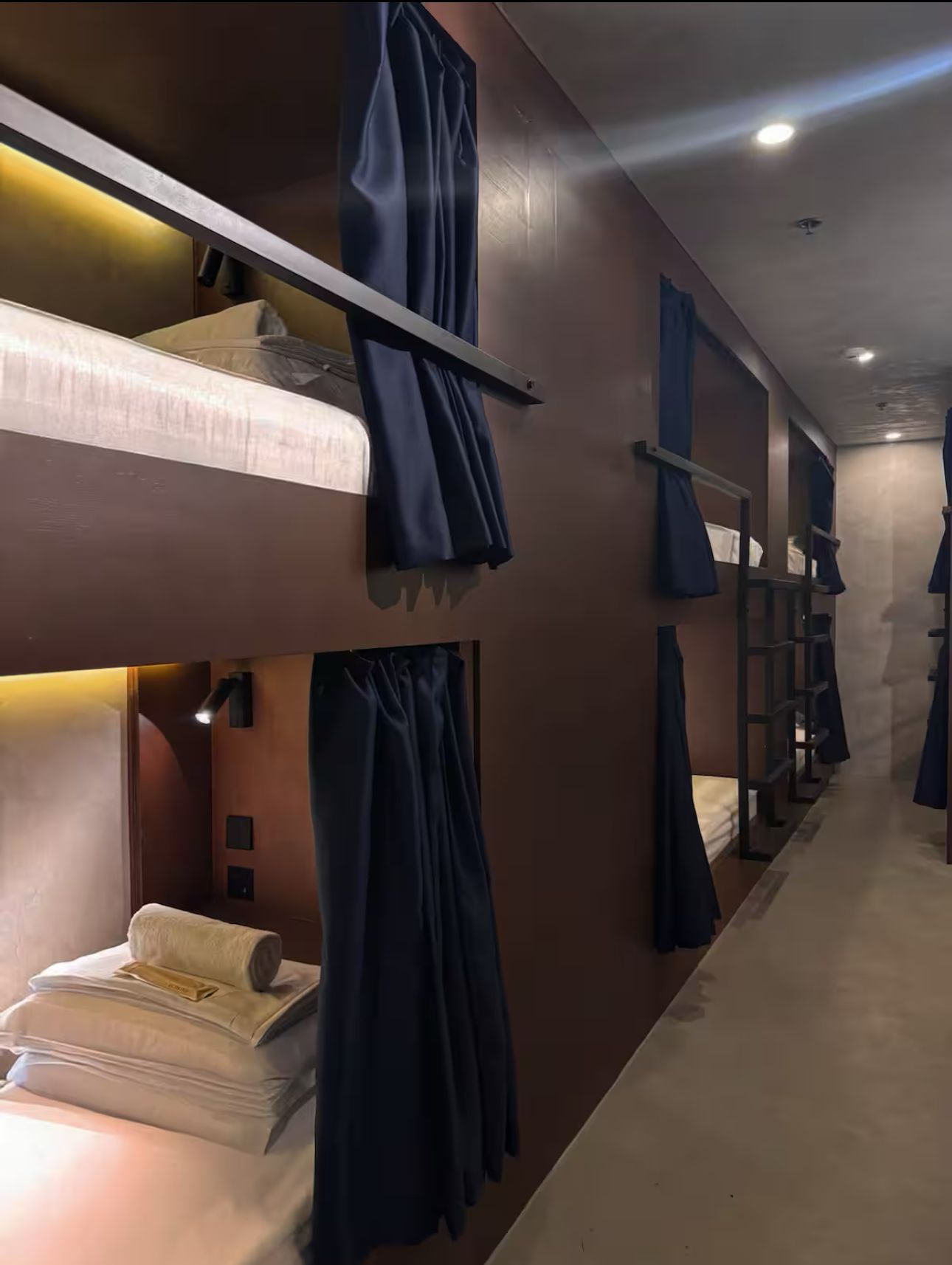 A row of bunk beds in a room with blue curtains