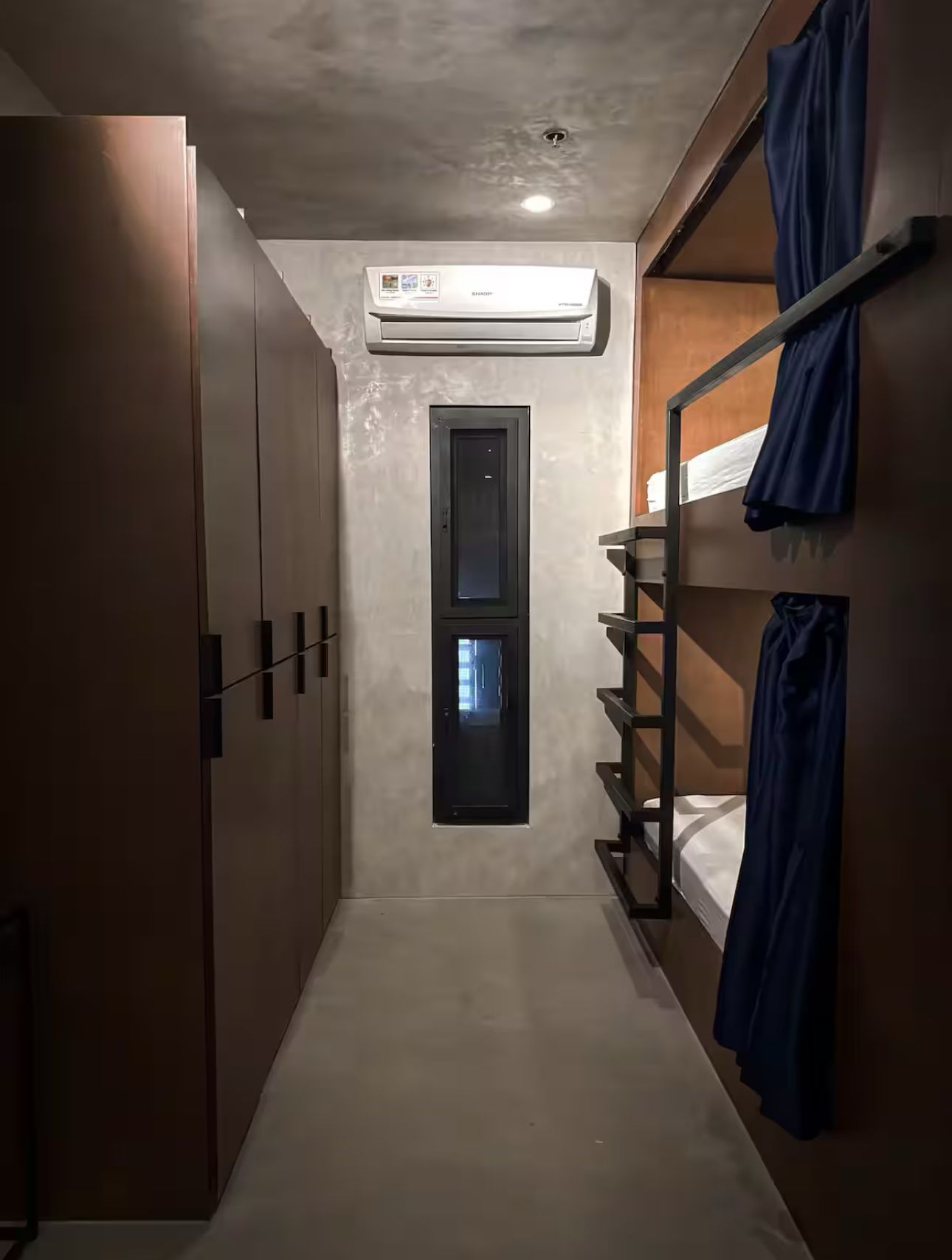 A long hallway with bunk beds and a window.