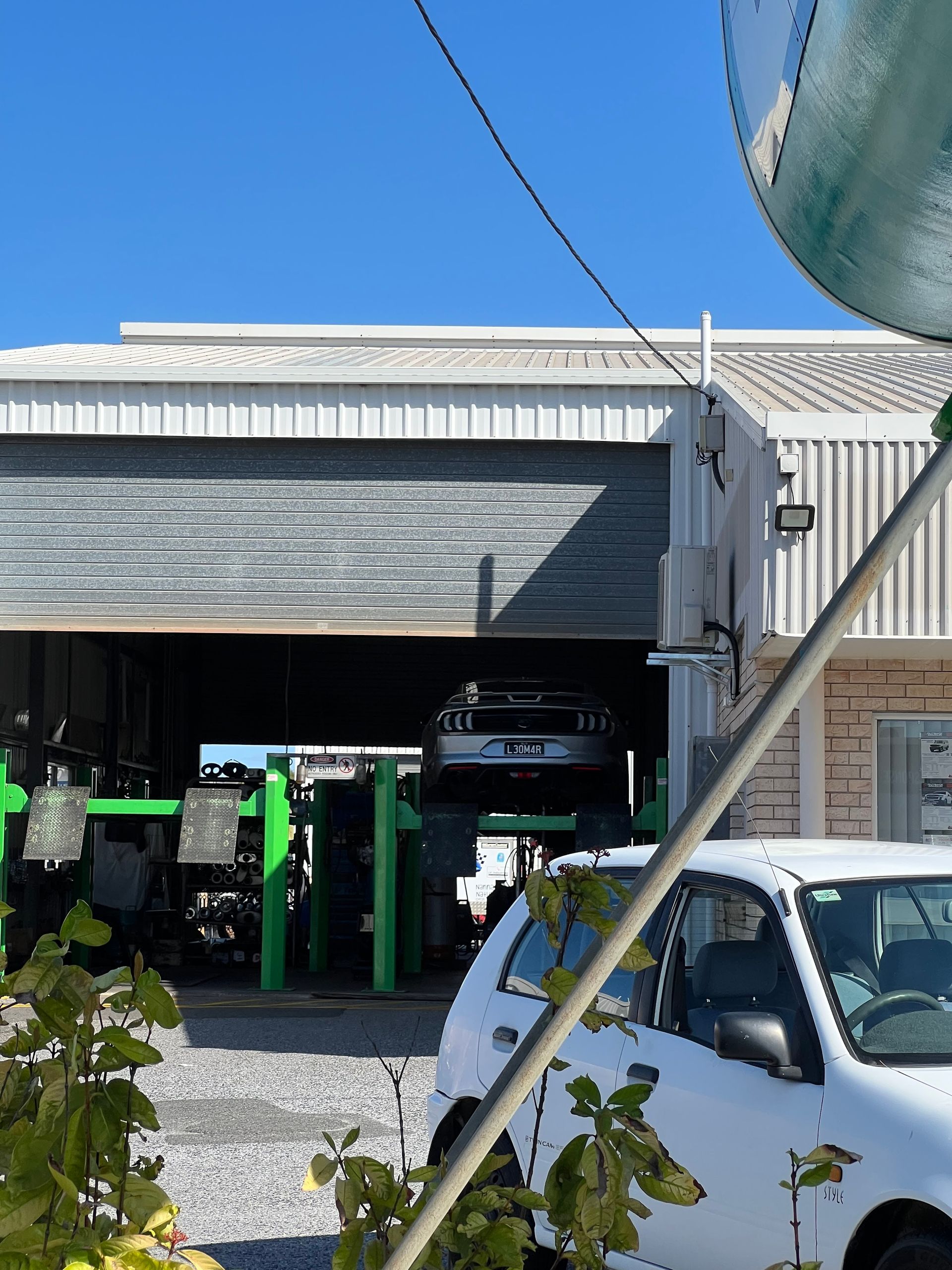 Car on a Lift Inside a Garage With a Partially Open Door — Gladstone Mufflers & Suspension In Gladstone Central, QLD