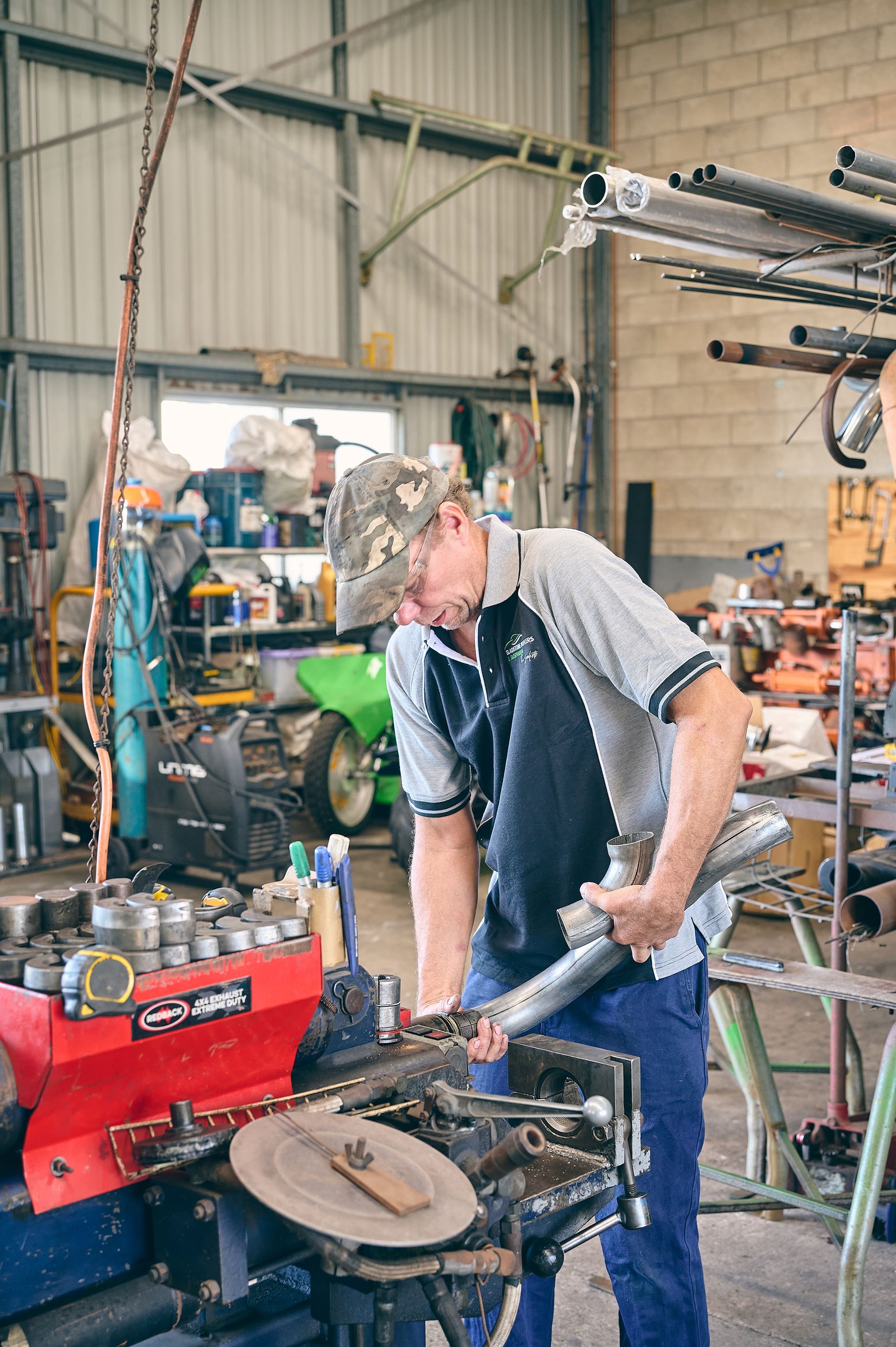 Man in Hat Working With Metal Tools — Gladstone Mufflers & Suspension In Gladstone Central, QLD