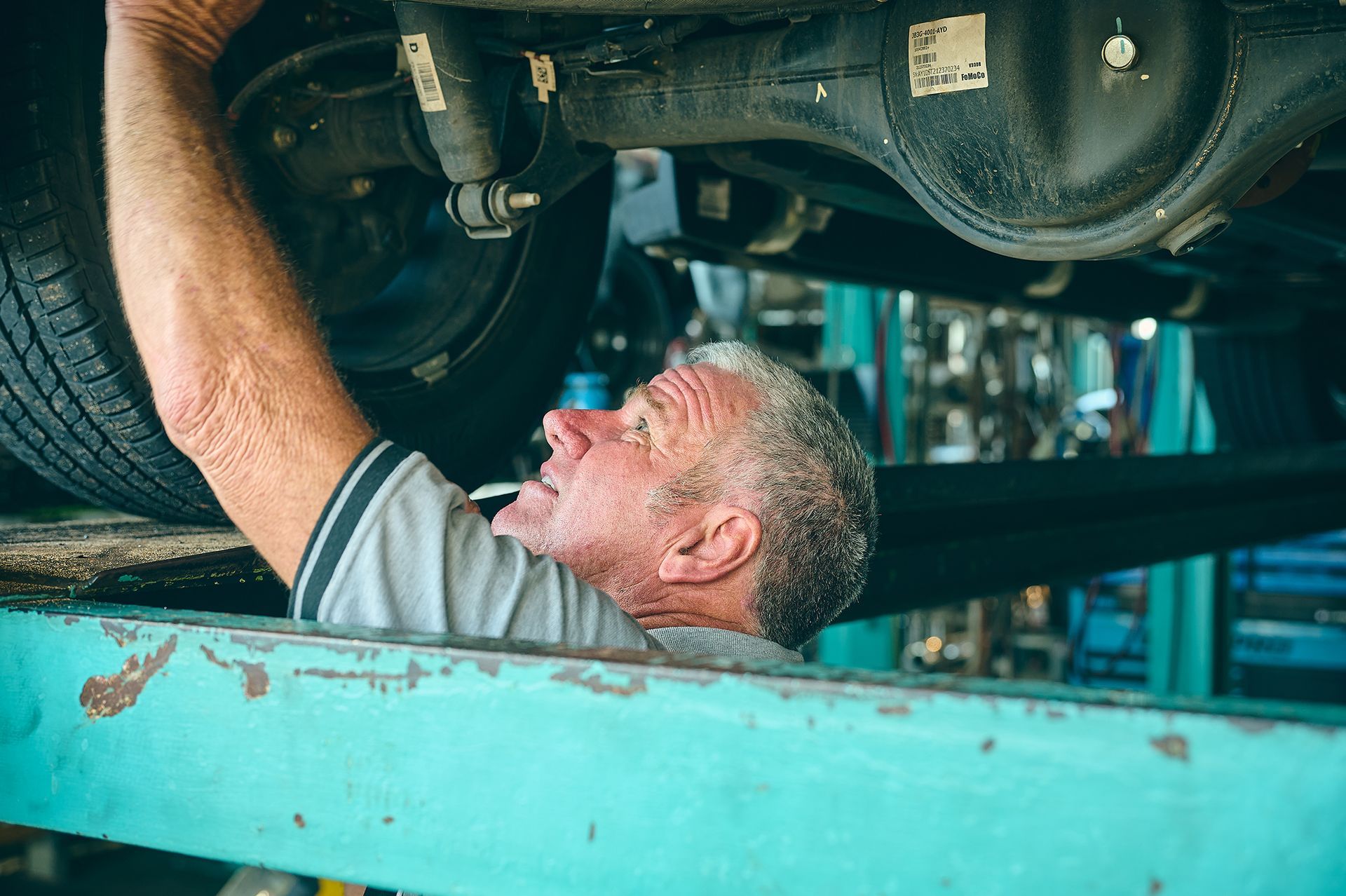 Mechanic Working Under a Car on a Lift — Gladstone Mufflers & Suspension In Gladstone Central, QLD