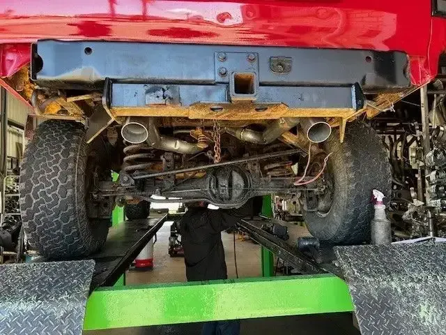 Rear of Red Truck on Lift. Showing Tires — Gladstone Mufflers & Suspension In Gladstone Central, QLD