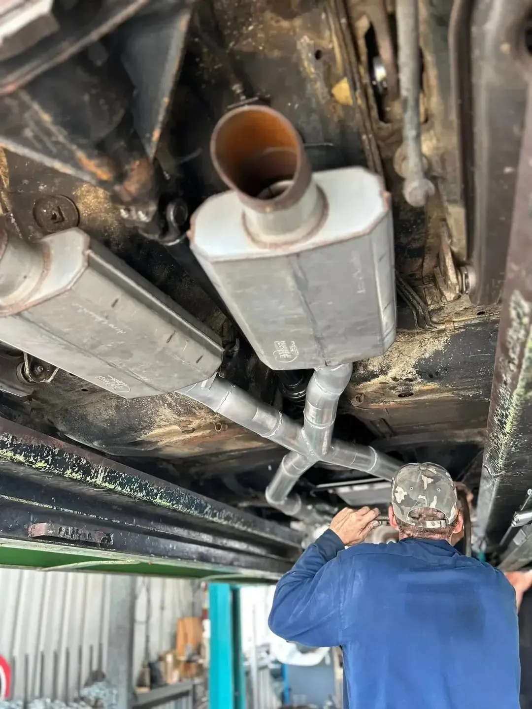 Man Working on Car's Exhaust System — Gladstone Mufflers & Suspension In Gladstone Central, QLD