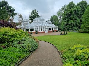 A greenhouse in a park with a path leading to it.