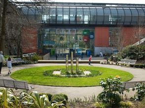 A group of people are walking in a park in front of a building.