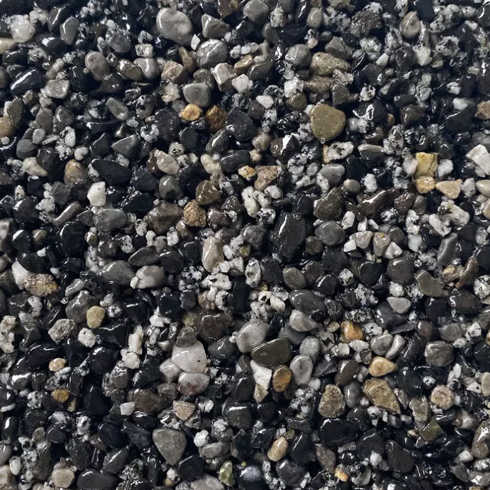 Close-up of a surface covered with small, mixed-color pebbles, including black, gray, and tan.