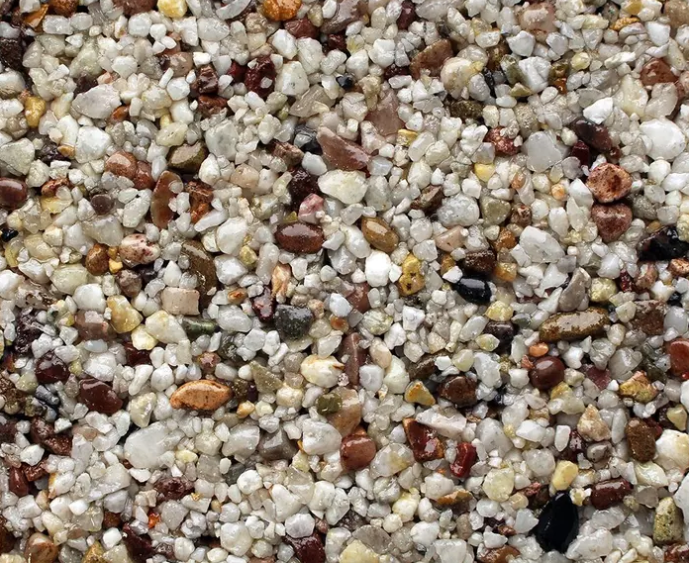 Gravel driveway in front of a brick house, with a tiled border and front door visible.