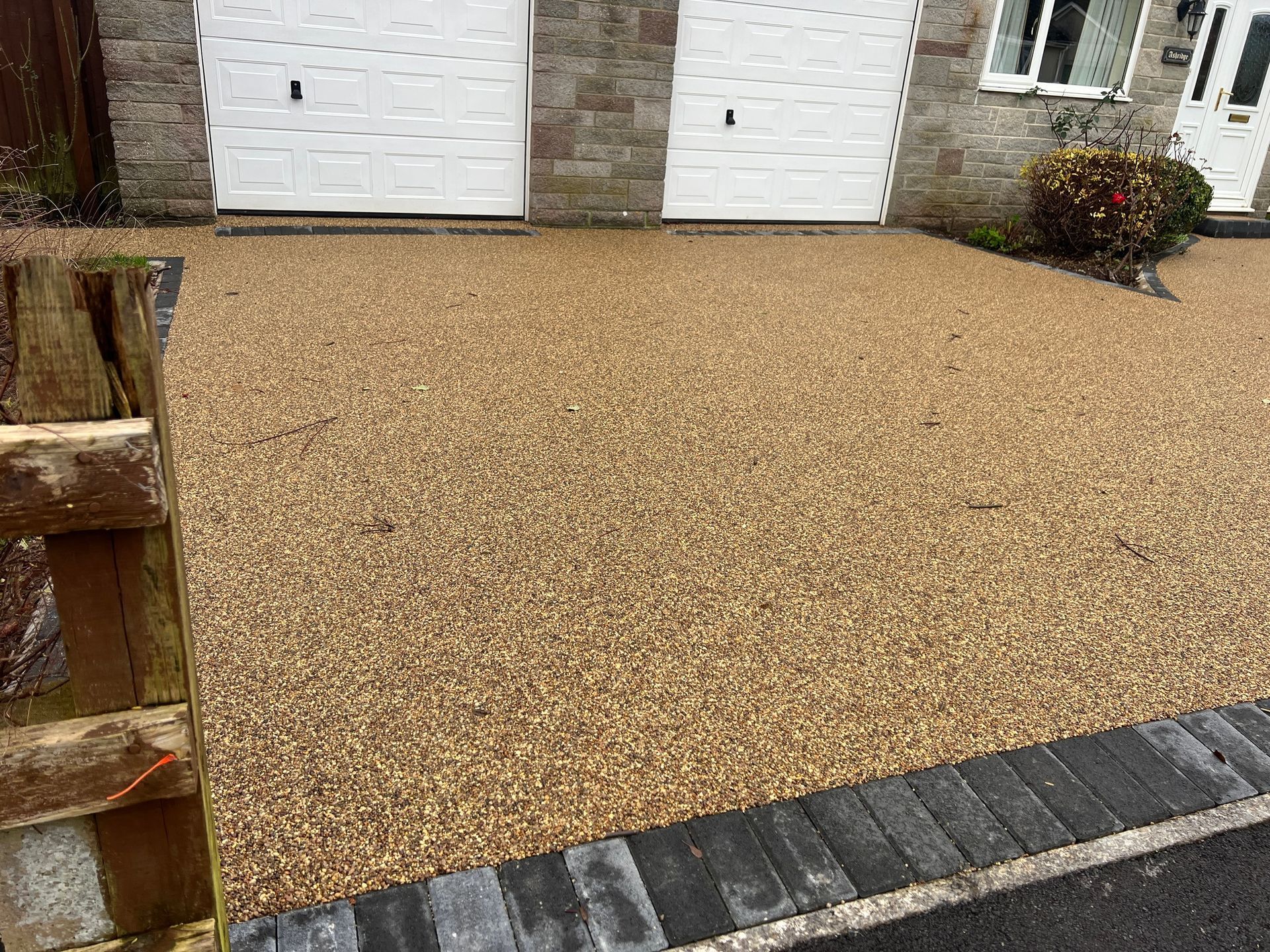 A gravel pathway in front of a house with two garage doors in Rochdale.