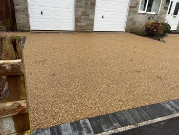 A gravel pathway in front of a house with two garage doors in Rochdale.