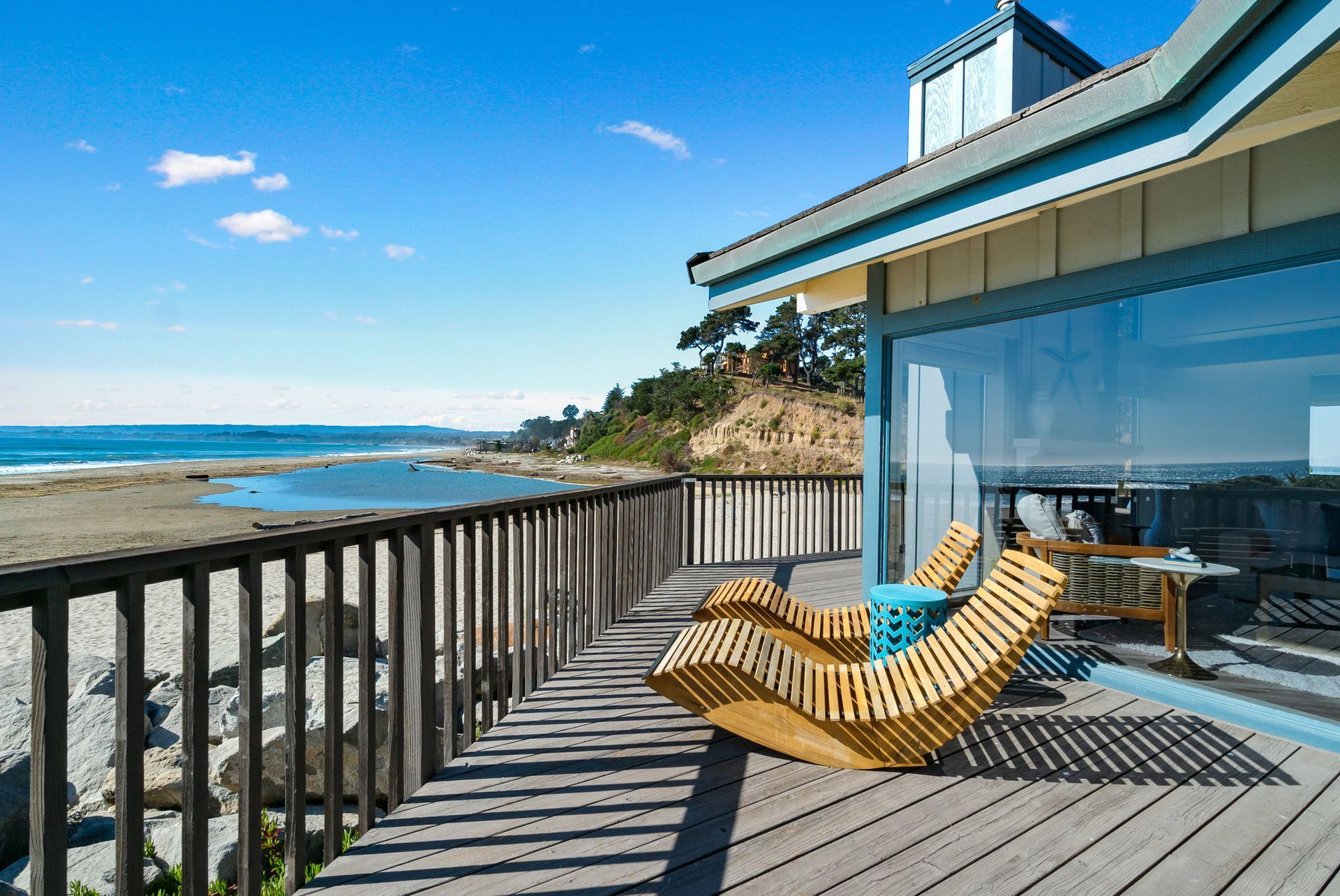 there are two chairs on the deck of a house with a view of the ocean .