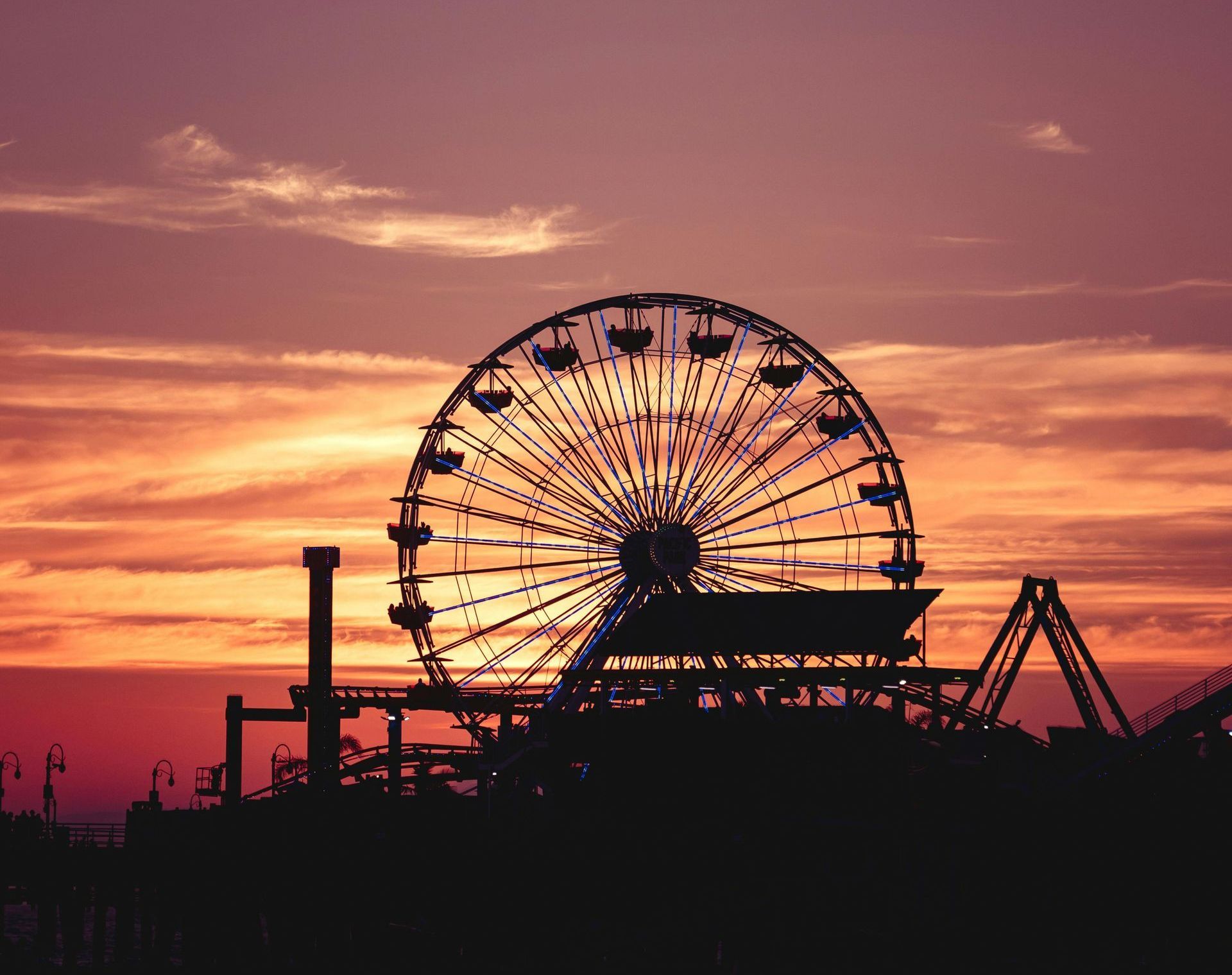 A Ferris wheel is silhouetted against a sunset sky.