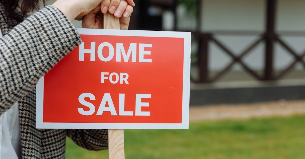 A woman is holding a home for sale sign in front of a house.