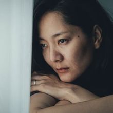 Asian woman looking through a window