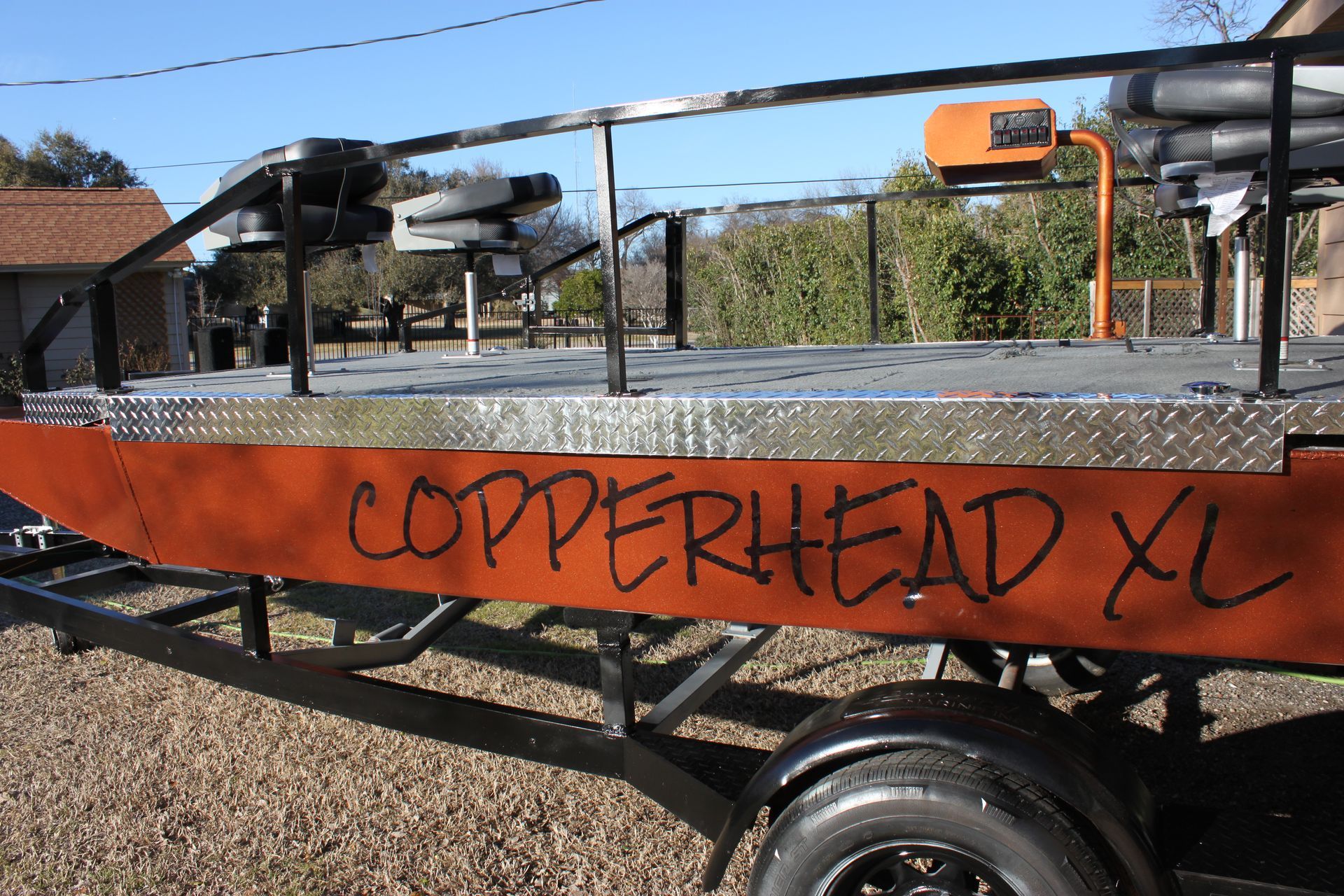 Copperhead XL orange boat on a trailer, black frame, diamond plate, outdoor setting.