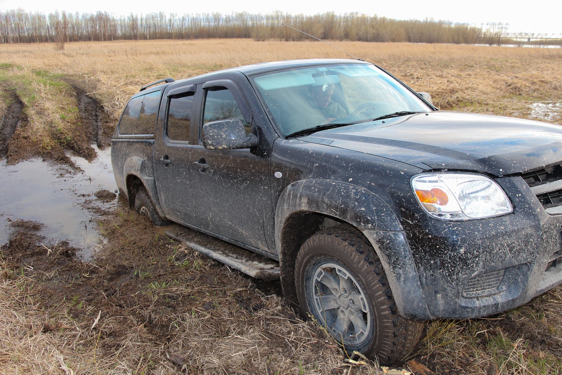 A black truck is stuck in the mud in a field