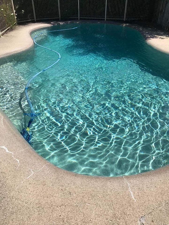 A Large Swimming Pool With a Vacuum Cleaner in It — Penguin Pools In Robina, QLD