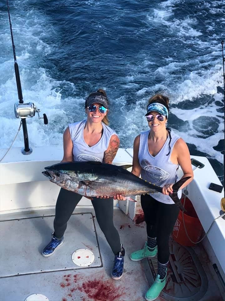 two ladies carrying a big tuna