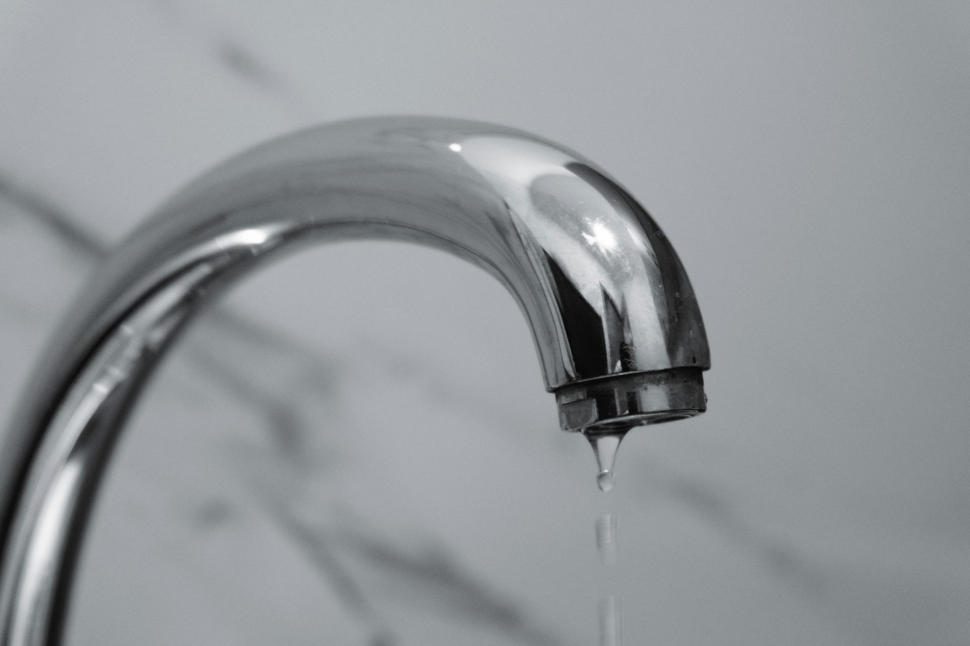 Chrome faucet dripping water over a sink
