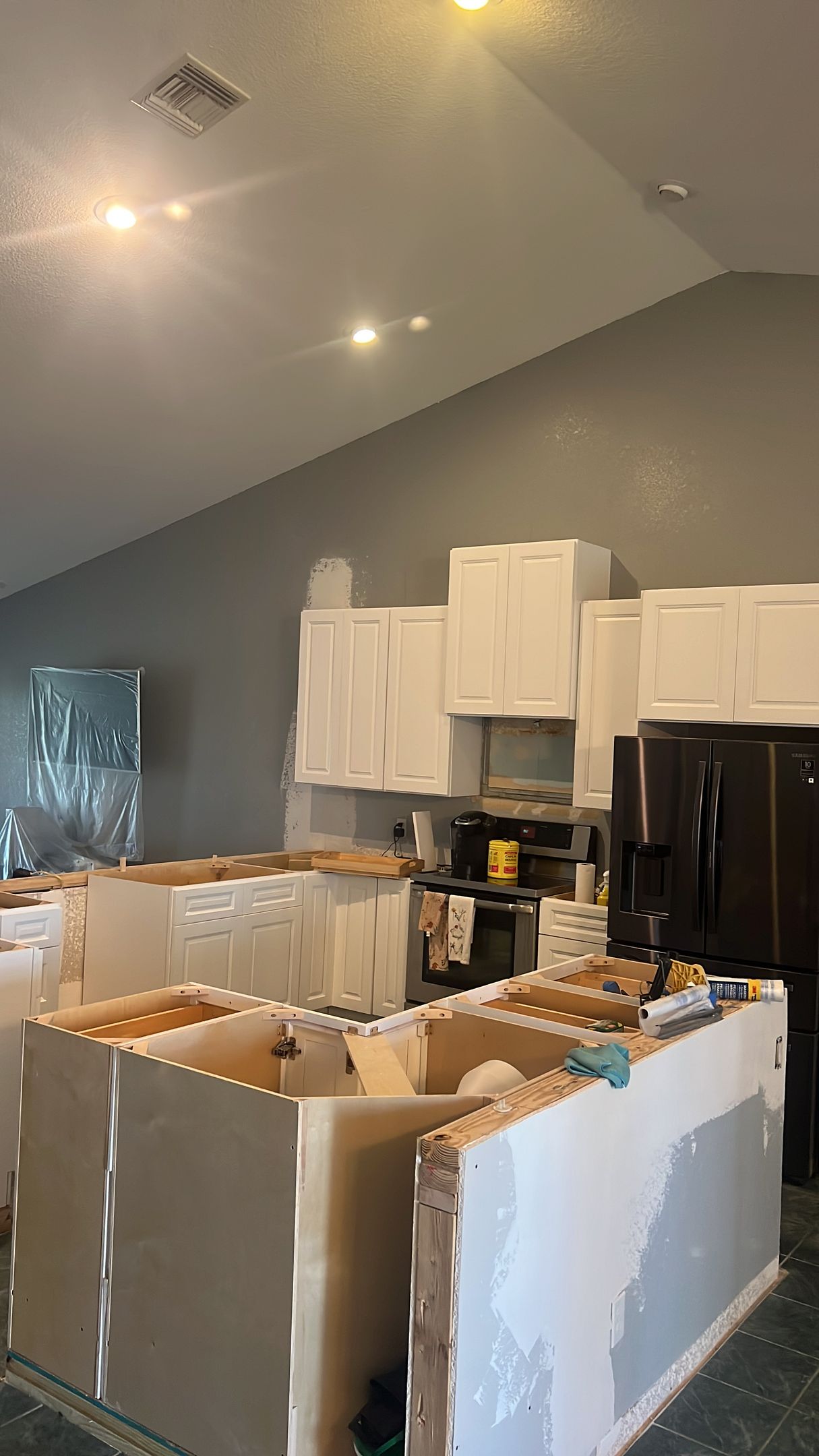 A kitchen is being remodeled with white cabinets and black appliances.