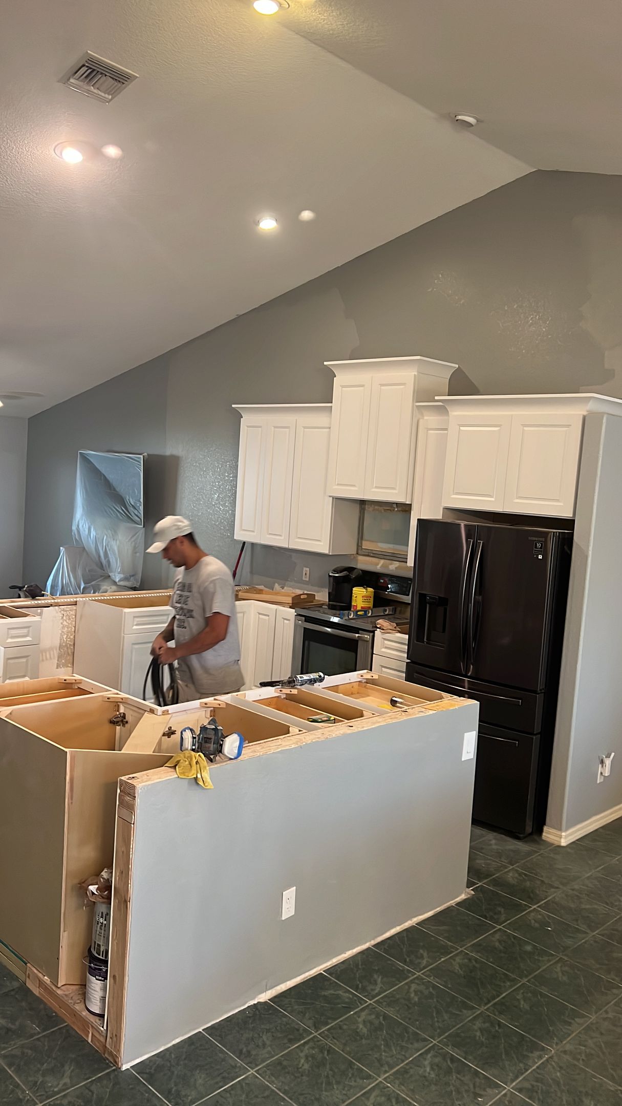 A man is working on a kitchen in a house under construction.