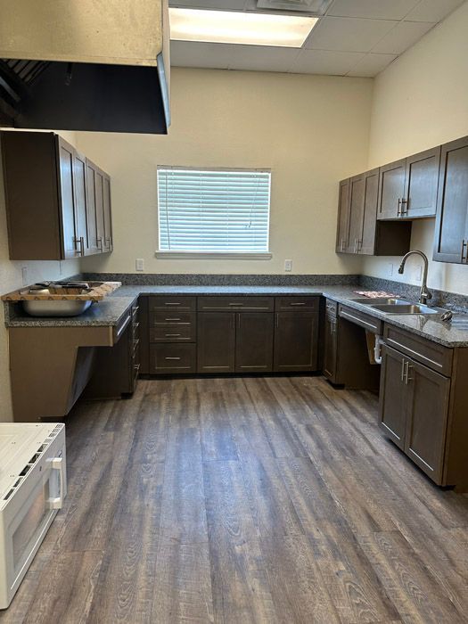 A kitchen with wooden floors and cabinets and a window.