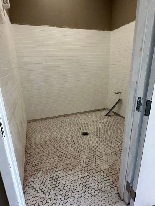 A bathroom with white tiles and a hexagonal tile floor.