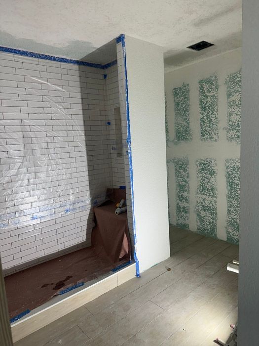 A bathroom with white brick walls and a walk in shower.
