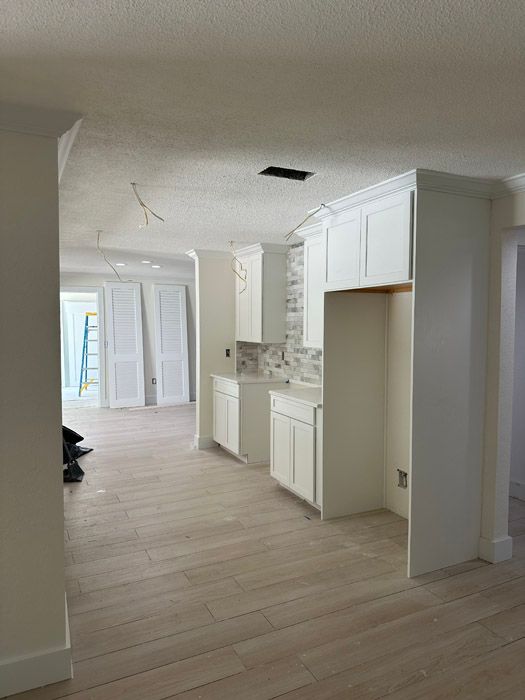 A kitchen with white cabinets and wooden floors is being remodeled.