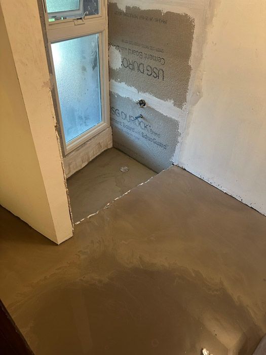 A room with a window and a concrete floor.