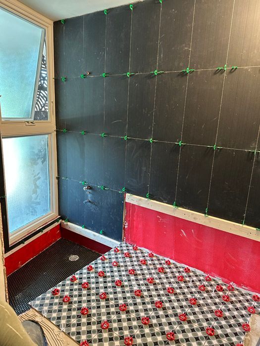 A bathroom with a black wall and a checkered floor.