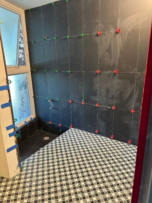 A bathroom with a black tile wall and a black and white checkered floor.