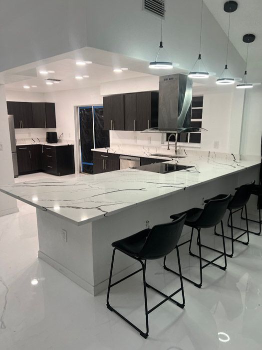 A kitchen with white counter tops and black chairs
