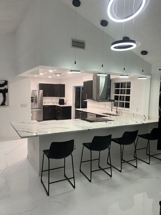 A kitchen with white counter tops and black chairs