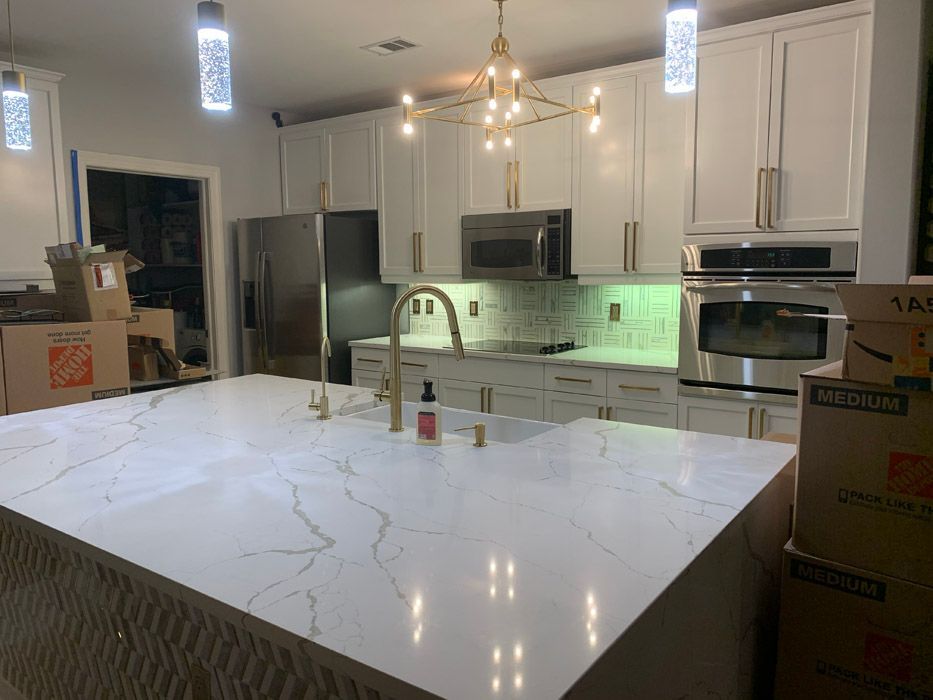 A kitchen with white cabinets , stainless steel appliances , and a large island.