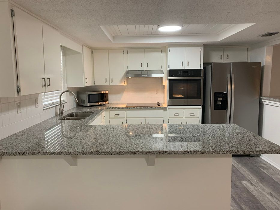 A kitchen with granite counter tops and white cabinets