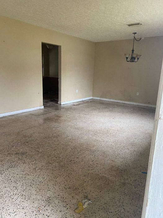 An empty living room with a chandelier hanging from the ceiling.