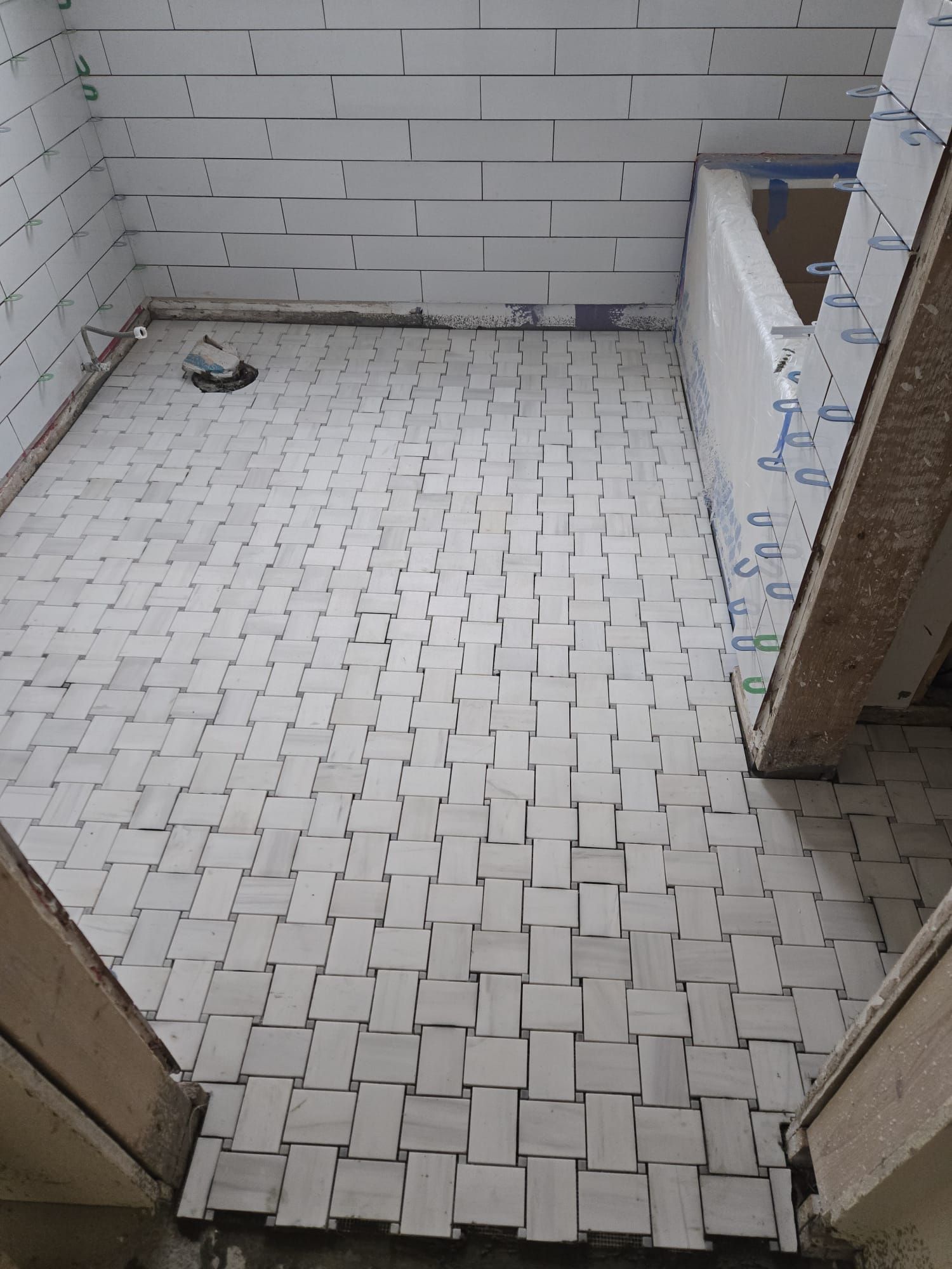 A bathroom with white tiles on the floor and walls.