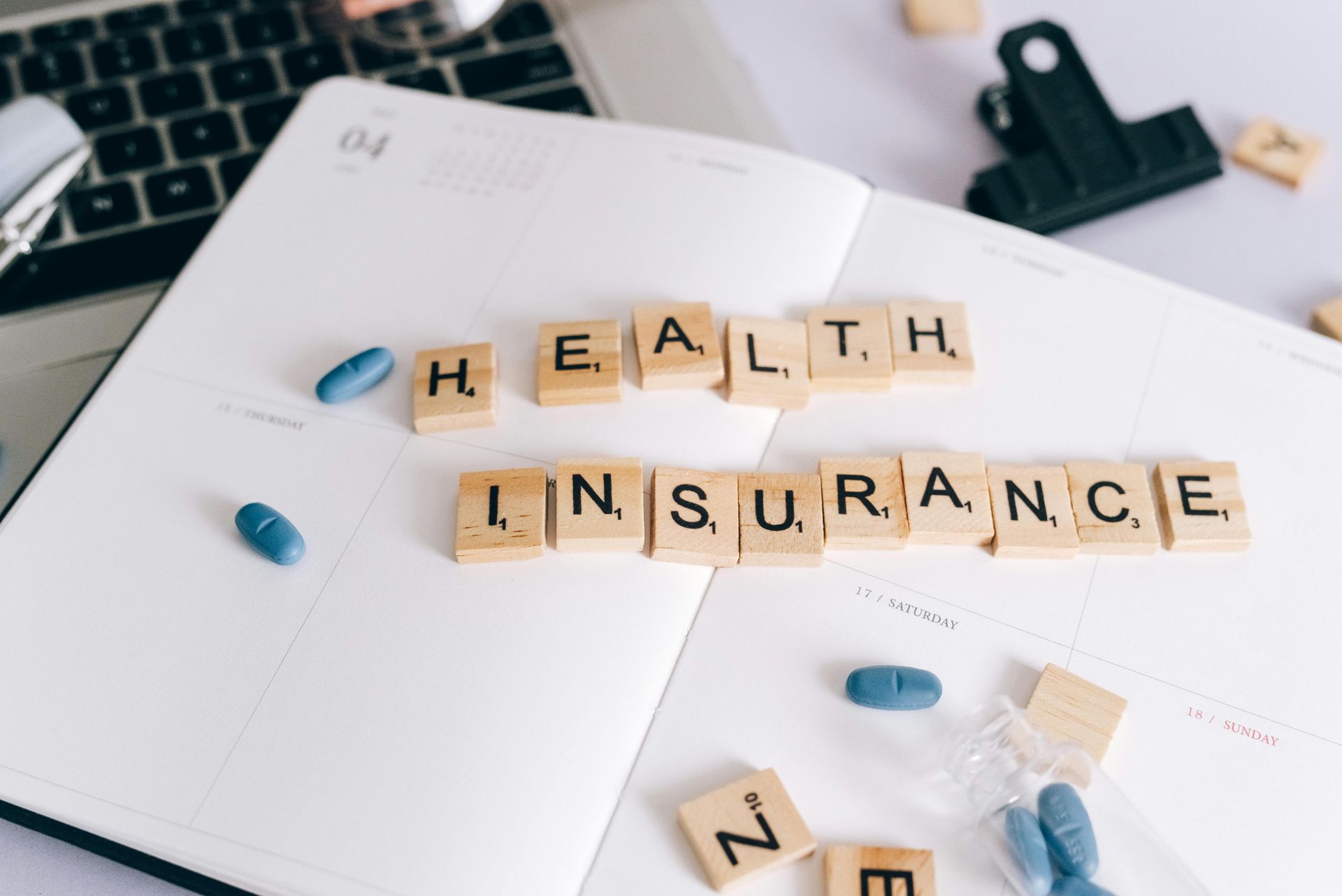 The words "health insurance" in scrabble letters are lying on a book