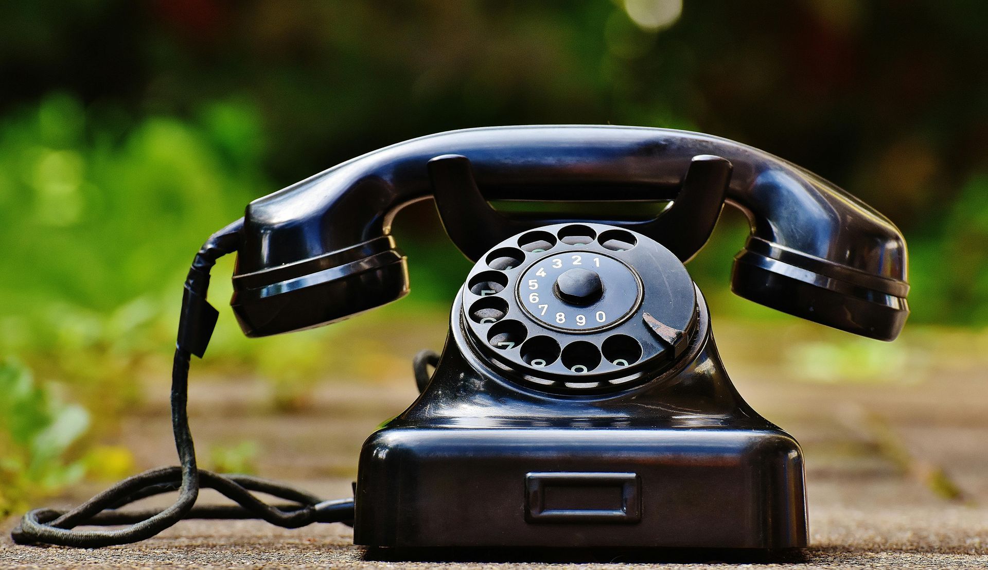 An old rotary dial phone is sitting on a window ledge