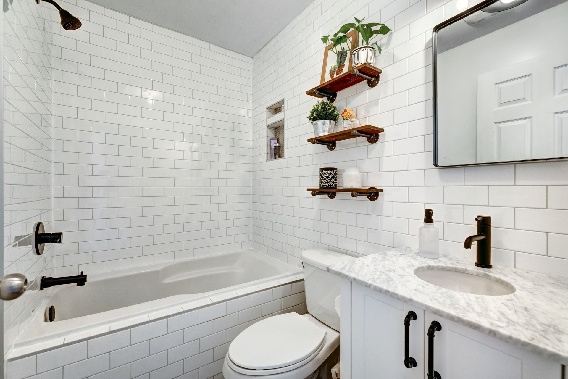 a bathroom with white tiles , a toilet , sink and bathtub .