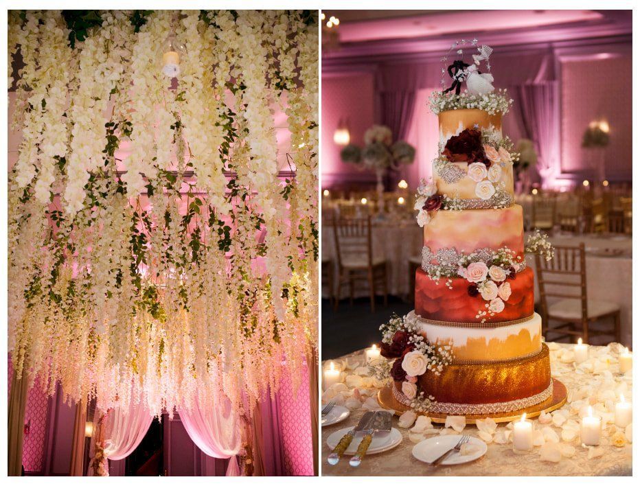 A wedding cake is sitting on a table in a room with flowers hanging from the ceiling.