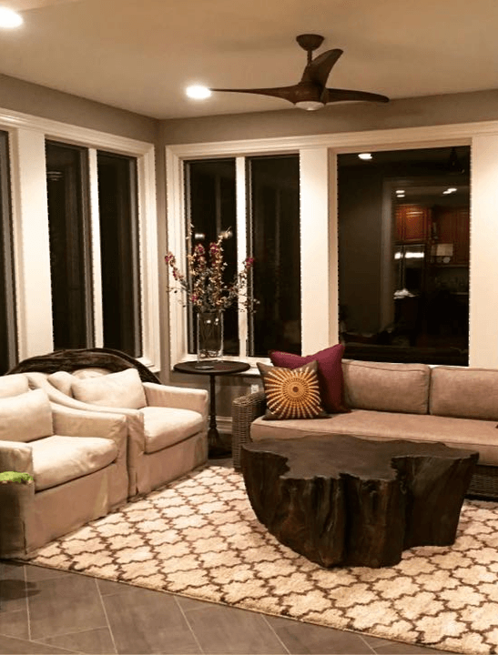 A living room with a couch , chairs , a coffee table and a ceiling fan.