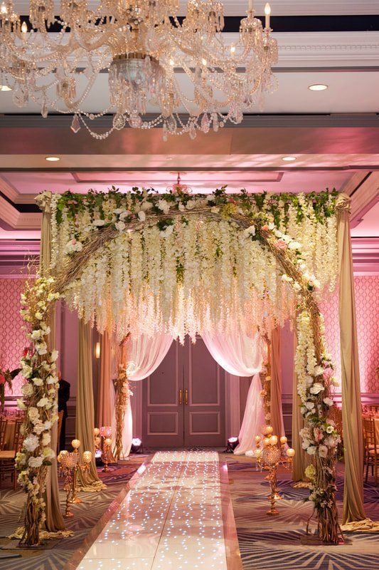 A wedding ceremony is taking place in a room decorated with flowers and a chandelier.