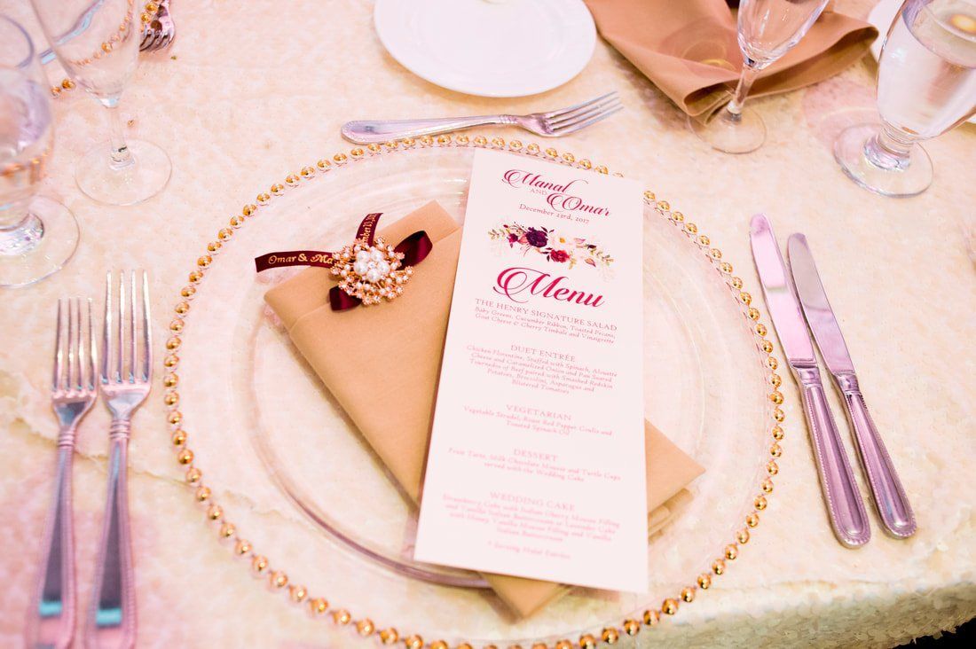 A place setting for a wedding reception with a menu on a plate.