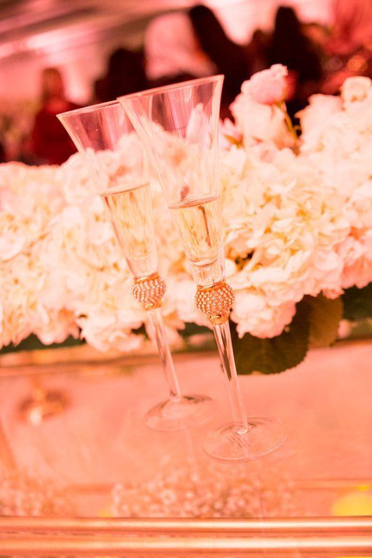 Two champagne flutes are sitting on a table next to flowers.