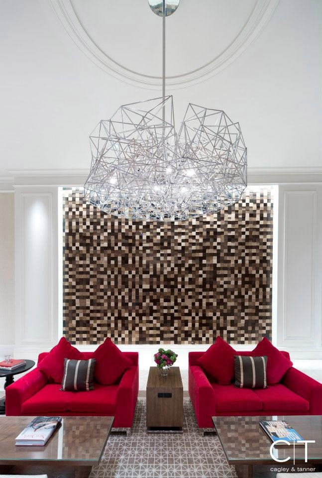 A living room with two red chairs and a chandelier