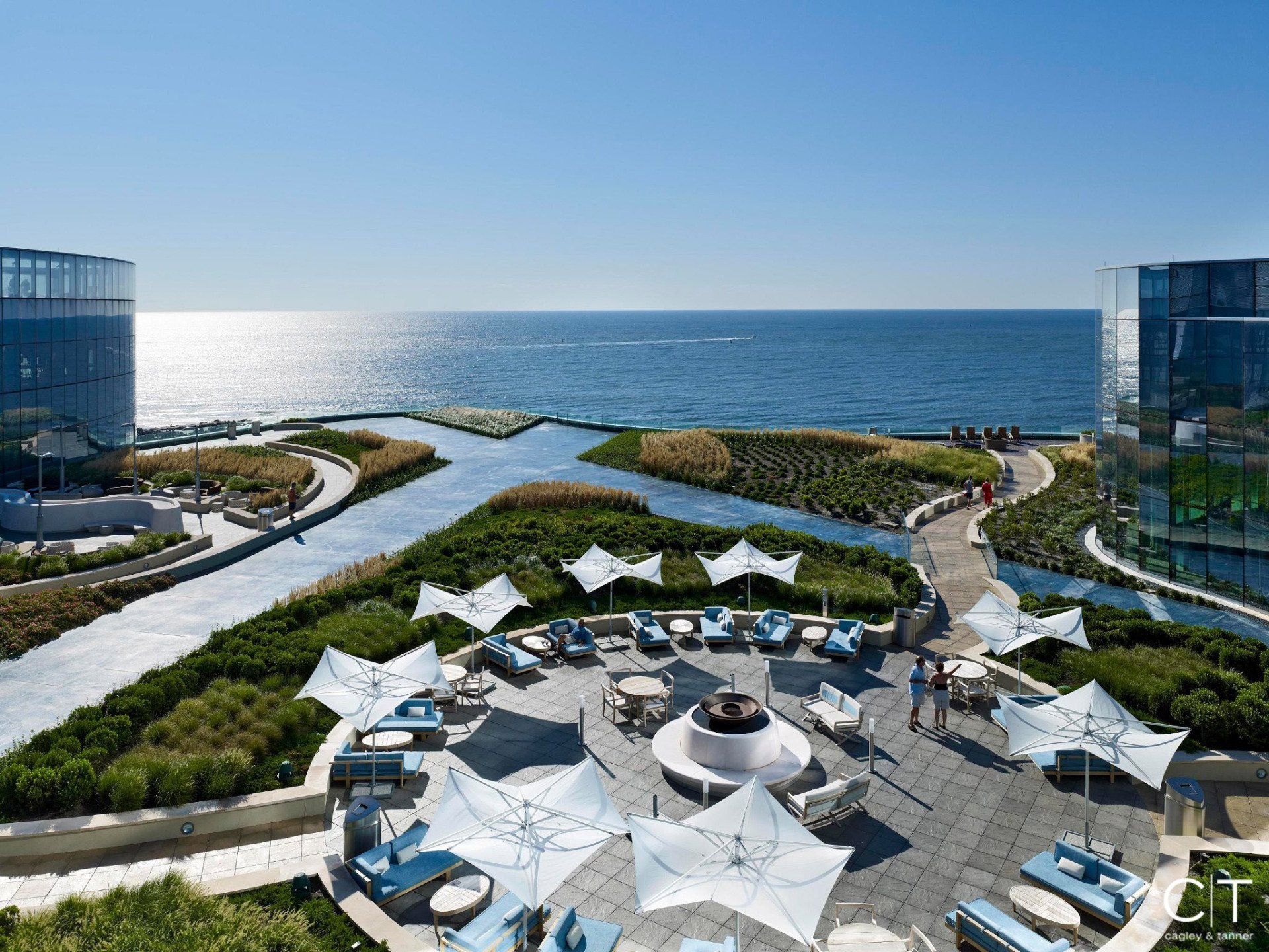 An aerial view of a patio with umbrellas and chairs overlooking the ocean