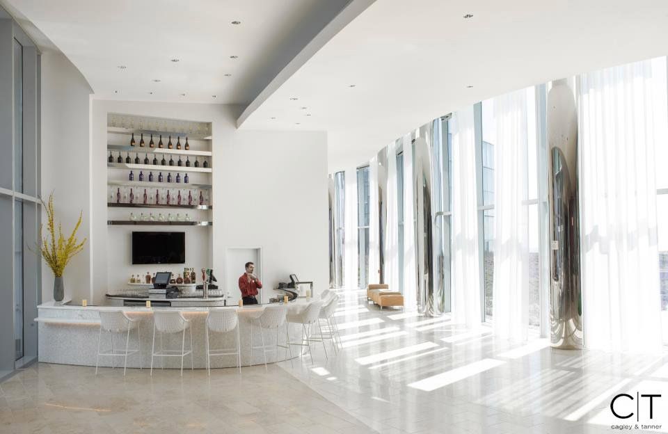A man is standing at a bar in a large room with a lot of windows.