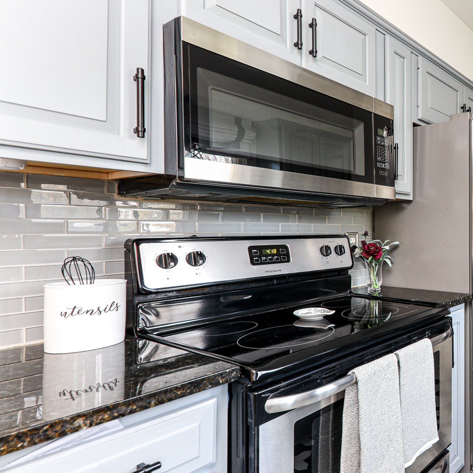 A kitchen with a stove , microwave , oven and cabinets.