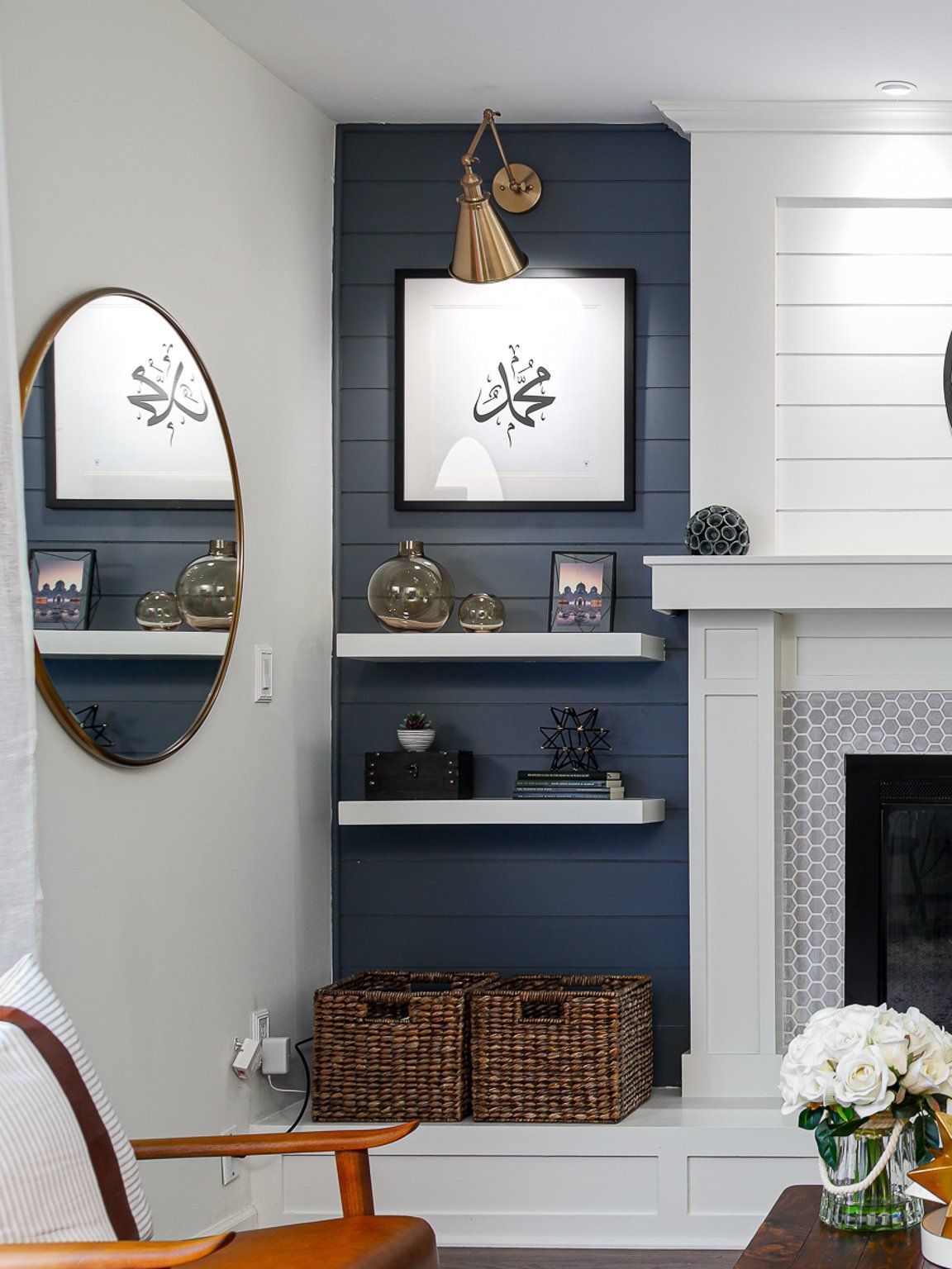 A living room with a fireplace , shelves , a chair and a mirror.